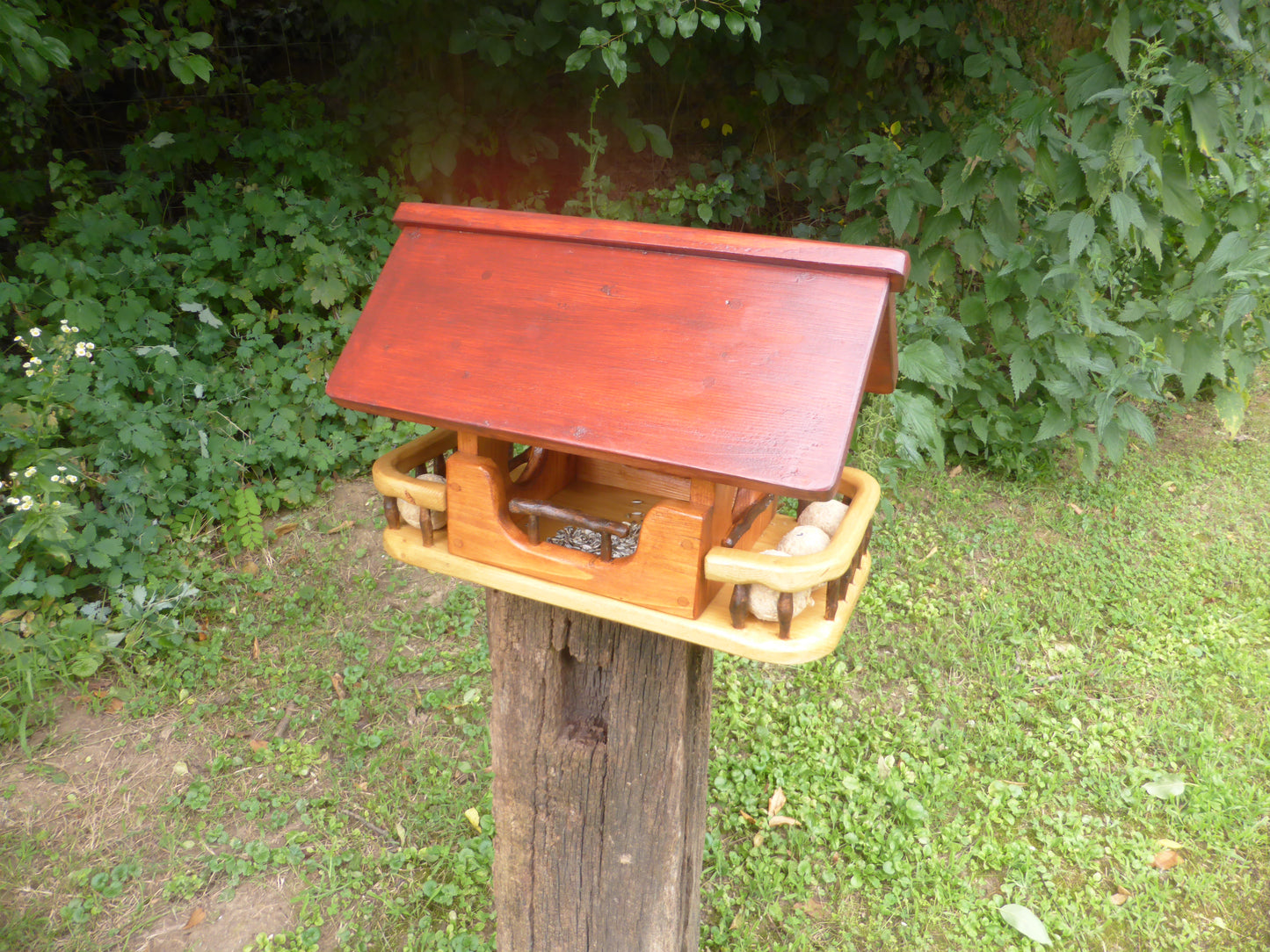 Vogelfutterhaus mit rotem  Dach und   Meisenknödelhalter